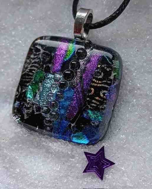 Row of handmade fused glass pendant necklaces in many colours
